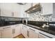Modern kitchen with white cabinets, black granite countertops, and unique patterned backsplash at 12950 W Quinto Dr, Sun City West, AZ 85375