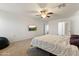 Spacious bedroom with neutral walls, carpeting, ceiling fan, and a wall-mounted TV for relaxation at 17043 N Avelino Dr, Maricopa, AZ 85138