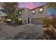 Two-story home featuring a desert-style landscape and a two car garage is awash in pink light from the setting sun at 17043 N Avelino Dr, Maricopa, AZ 85138
