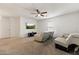 Spacious living room with plush carpeting, ceiling fan, and comfortable, reclining leather furniture at 17043 N Avelino Dr, Maricopa, AZ 85138