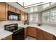 Efficient kitchen with white countertops, wood cabinets, and black appliances, offering a practical cooking space at 1839 E Vinedo Ln, Tempe, AZ 85284