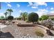 Landscaped backyard featuring rock water feature, well manicured trees and desert plants at 19722 N Regents Park Dr, Surprise, AZ 85387