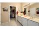 Bathroom with dual sinks, large mirror, and walk-in closet showcasing lots of storage at 19722 N Regents Park Dr, Surprise, AZ 85387