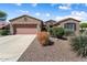 Well-maintained house featuring desert landscaping, mature shrubs, and a two-car garage at 19722 N Regents Park Dr, Surprise, AZ 85387