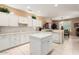 Bright kitchen featuring white cabinets, marble countertops, tile flooring and a center island at 19722 N Regents Park Dr, Surprise, AZ 85387