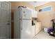 Efficient laundry room with washer, dryer, refrigerator, cabinets, and exterior access at 19722 N Regents Park Dr, Surprise, AZ 85387