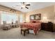 Comfortable main bedroom with a large window, ceiling fan, sitting area, and ensuite bathroom at 19722 N Regents Park Dr, Surprise, AZ 85387