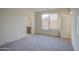 Shows a bright carpeted bedroom with a window, light walls and trim, and a door leading to the ensuite bathroom at 20162 W Buchanan St, Buckeye, AZ 85326