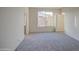 Shows a carpeted bedroom with a window, light walls and trim, and a door leading to the ensuite bathroom at 20162 W Buchanan St, Buckeye, AZ 85326