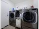 Practical laundry room with full-size washer and dryer, shelf storage, and a utility sink at 21070 N Alexis Ave, Maricopa, AZ 85138