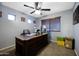 Home office with large desk, ceiling fan, carpet, and natural light from two windows at 21070 N Alexis Ave, Maricopa, AZ 85138
