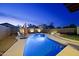 A backyard pool with an umbrella covered seating area, basketball hoop, and outdoor lighting at 21070 N Alexis Ave, Maricopa, AZ 85138