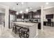 A modern kitchen with dark cabinets, granite countertops, and a large center island with seating at 22607 W Antelope Trl, Buckeye, AZ 85326