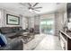 Bright living room with modern furniture, neutral tile floors, a large ceiling fan, and sliding glass doors at 22607 W Antelope Trl, Buckeye, AZ 85326