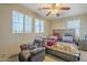 Comfortable bedroom features a cozy recliner, multiple windows, and ceiling fan offering a relaxing retreat at 26842 N 176Th Ln, Surprise, AZ 85387