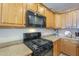 Close-up of a kitchen featuring oak cabinets, stone countertops, and black appliances at 26842 N 176Th Ln, Surprise, AZ 85387