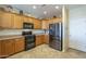 Well-lit kitchen with oak cabinets, black appliances, and stone countertops at 26842 N 176Th Ln, Surprise, AZ 85387