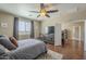 Main bedroom features wood flooring, ceiling fan, TV console, and a cozy decorative rug at 26842 N 176Th Ln, Surprise, AZ 85387