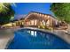 This back exterior features a pool, covered patio, and lights illuminating the landscaping around the home at 2894 E Melody Ln, Gilbert, AZ 85234