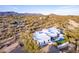 An aerial view of a modern white home in a desert landscape, showcasing its pool and surrounding natural beauty at 37646 N Dream St, Carefree, AZ 85377