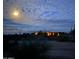 Distant desert home illuminated at night under a full moon, set against a backdrop of cloudy skies and arid landscape at 37646 N Dream St, Carefree, AZ 85377