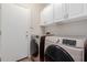 This laundry room features a washer, a dryer, and white storage cabinets at 38167 W Santa Clara Ave, Maricopa, AZ 85138