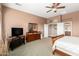 Spacious main bedroom with a ceiling fan, dresser, TV, and entrance to the attached bathroom at 41961 W Centennial Rd, Maricopa, AZ 85138