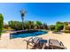 A backyard pool with a lush garden, a spa, and a lounge area creates a serene retreat at 41961 W Centennial Rd, Maricopa, AZ 85138