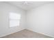 An empty bedroom featuring carpet, white walls, a ceiling fan, and a window at 44583 W Windrose Dr, Maricopa, AZ 85138