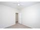 An empty bedroom featuring carpet, white walls, a ceiling fan, and an open door at 44583 W Windrose Dr, Maricopa, AZ 85138