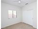 An empty bedroom featuring carpet, white walls, a ceiling fan, a window and a closet at 44583 W Windrose Dr, Maricopa, AZ 85138