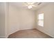 A simple bedroom with tan carpet, a ceiling fan, one window, and light-colored walls at 44583 W Windrose Dr, Maricopa, AZ 85138
