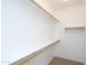 A walk-in closet with white walls and shelves, and a beige carpeted floor, offering ample storage space at 44583 W Windrose Dr, Maricopa, AZ 85138