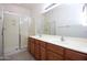 Bathroom featuring a glass shower and double sinks set into wood cabinets with a large mirror at 45071 W Yucca Ln, Maricopa, AZ 85139