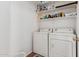 Functional laundry room equipped with white washer and dryer, along with upper storage shelves at 45564 W Sheridan Rd, Maricopa, AZ 85139