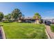 Charming home featuring a well-manicured lawn, mature trees and desert landscaping under a clear blue sky at 520 S Greenfield Rd # 22, Mesa, AZ 85206