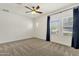 Bedroom with carpet, ceiling fan, two windows with blinds and dark blue curtains at 6204 S Banning St, Gilbert, AZ 85298