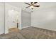Carpeted bedroom featuring a gray accent wall, ceiling fan, and view into another room at 6204 S Banning St, Gilbert, AZ 85298