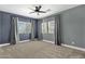 Spacious carpeted bedroom featuring large windows with gray curtains, a ceiling fan, and gray walls at 6204 S Banning St, Gilbert, AZ 85298