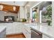 Modern kitchen features white cabinetry, stainless steel appliances, and a window over the farmhouse sink at 8336 S Homestead Ln, Tempe, AZ 85284