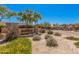 Stone-clad community entrance sign with lush desert landscaping, mature trees, and a gated entrance in the background at 8542 E Indigo St, Mesa, AZ 85207