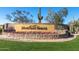 Landscaped community entrance sign for Mountain Bridge featuring mature desert vegetation and colorful flower beds at 8542 E Indigo St, Mesa, AZ 85207
