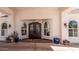 Elegant front entrance with arched windows, featuring custom iron doors and a welcoming courtyard in a desert landscaped setting at 9401 N 122Nd Pl, Scottsdale, AZ 85259