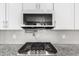 Close up of a stainless steel range, tiled backsplash and a modern overhead microwave at 10043 W Foothill Dr, Peoria, AZ 85383