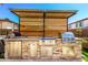 Modern outdoor kitchen with stone accents, stainless steel appliances, and a stylish pergola overhead at 10043 W Foothill Dr, Peoria, AZ 85383