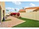 A spacious backyard with artificial grass, a brick-paved patio, and vibrant bougainvillea bushes at 11033 E Poinsettia Dr, Scottsdale, AZ 85259