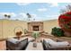 Cozy outdoor patio with fireplace, comfortable seating, brick pavers and vibrant foliage at 11033 E Poinsettia Dr, Scottsdale, AZ 85259