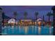 Community swimming pool featuring lounge chairs, shade structures, and palm trees at dusk at 13660 N 144Th Ln, Surprise, AZ 85379