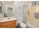 Bathroom with a single sink vanity with wood cabinets, a bathtub with a shower, and a window for light at 1569 E Princeton Ave, Gilbert, AZ 85234