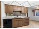 The kitchen showcases wood cabinets, a neutral countertop, tile backsplash, and black dishwasher at 16827 N 103Rd Ave, Sun City, AZ 85351
